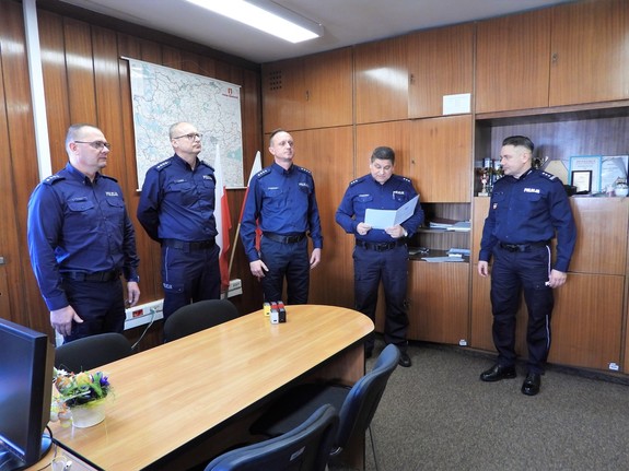 pięciu policjantów stojacych w pokoju podczas odczytywania rozkazu personalnego podczas mianowania komendanta komisariatu w Zabierzowie i zastępcy (2)