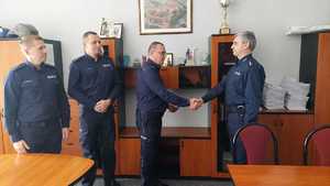 zastępca komendanta gratuluje nowemu kierownikowi, obok komendanci komisariatu w Skawinie